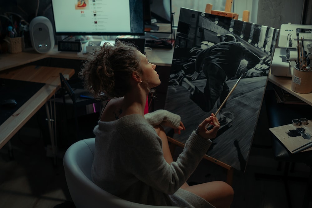 a woman sitting in a chair in front of a painting