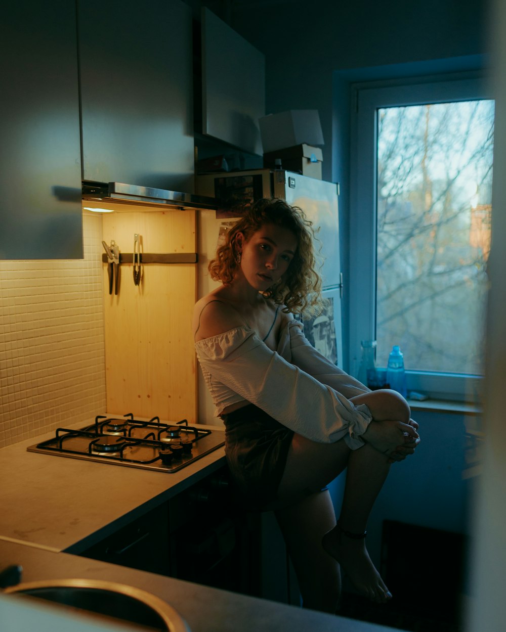 a woman sitting on a counter in a kitchen