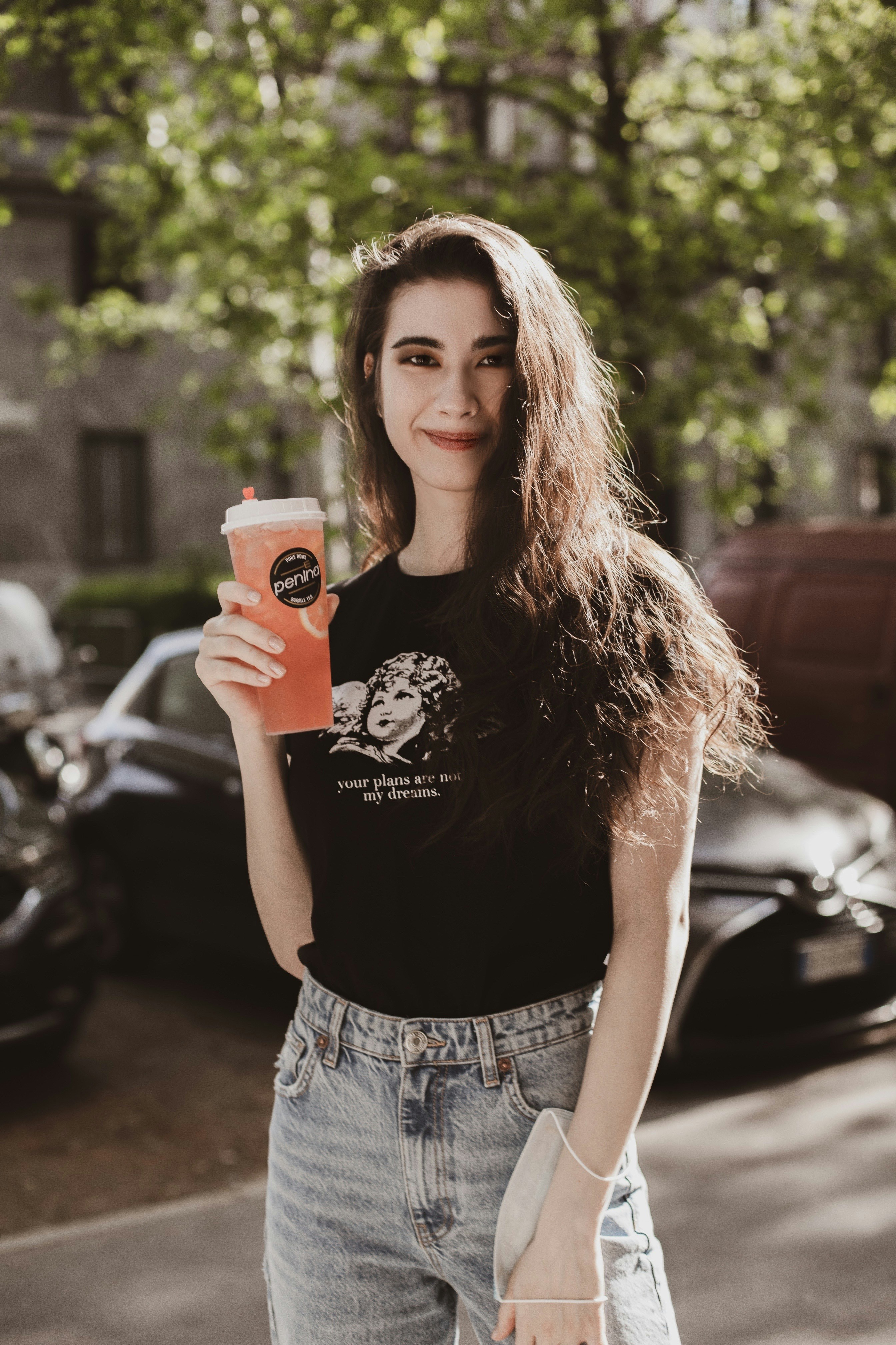 uma mulher segurando uma bebida e um telefone celular