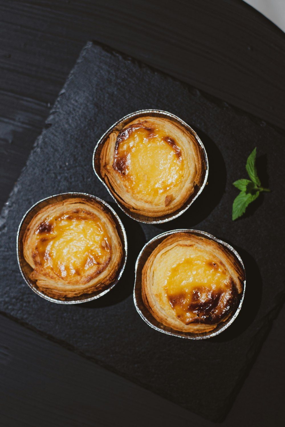 three small pies sitting on top of a black plate