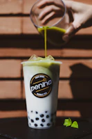 a person pours a green drink into a cup