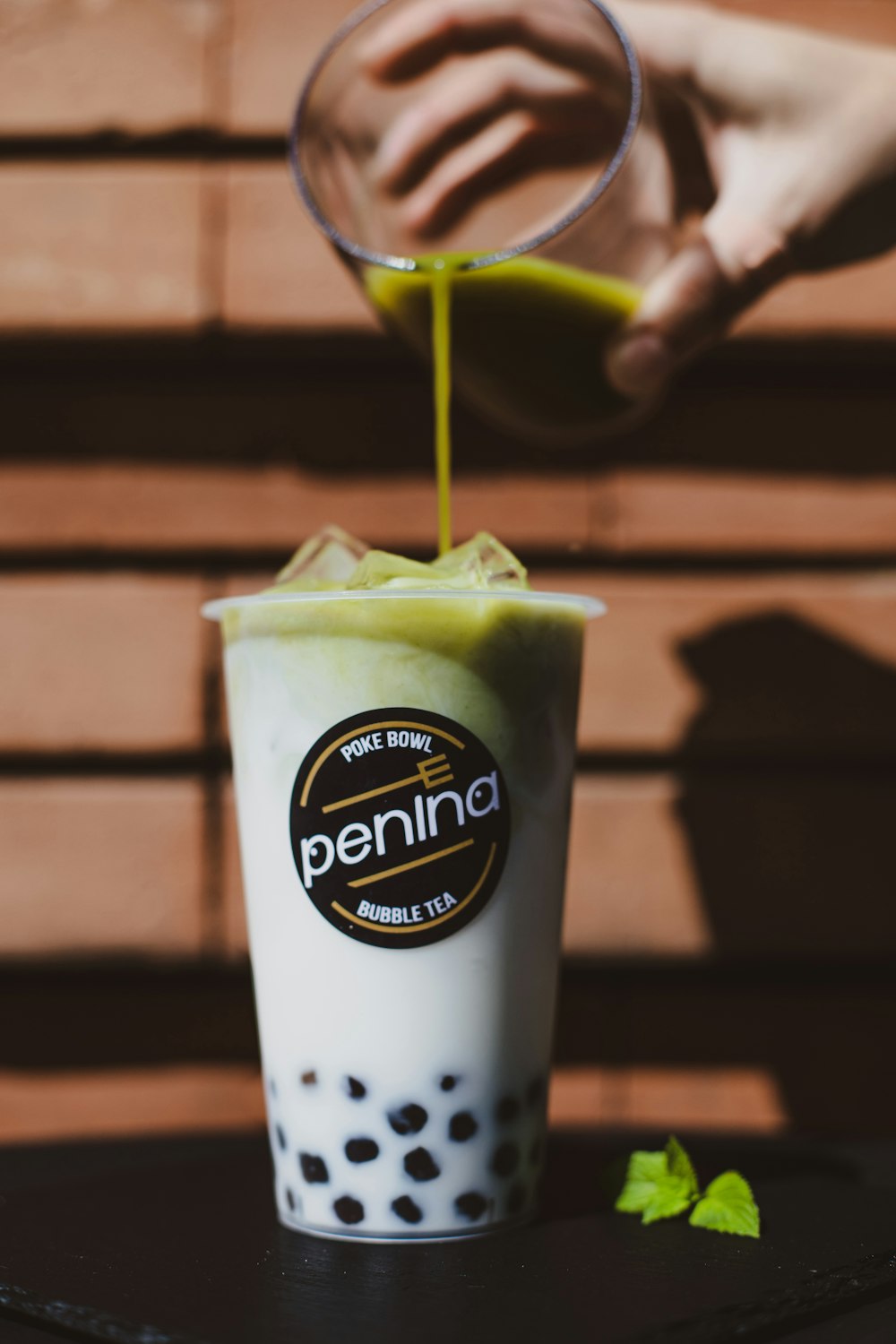 a person pours a green drink into a cup