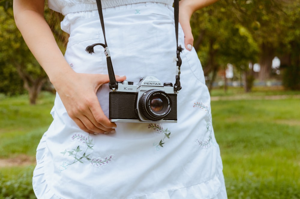 a woman in a white dress holding a camera