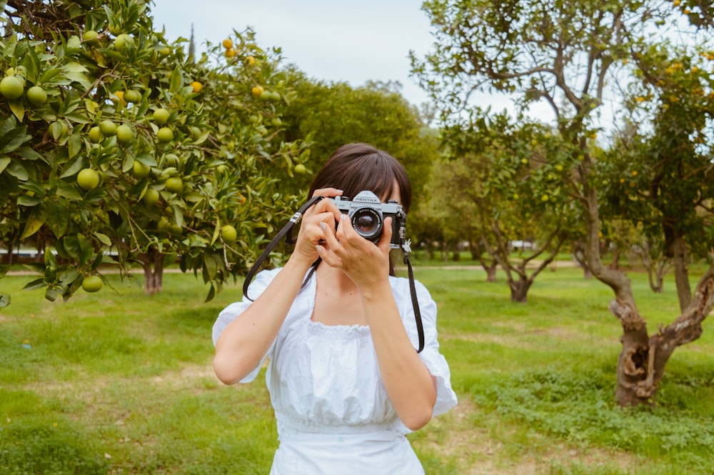 a woman taking a picture of an apple tree