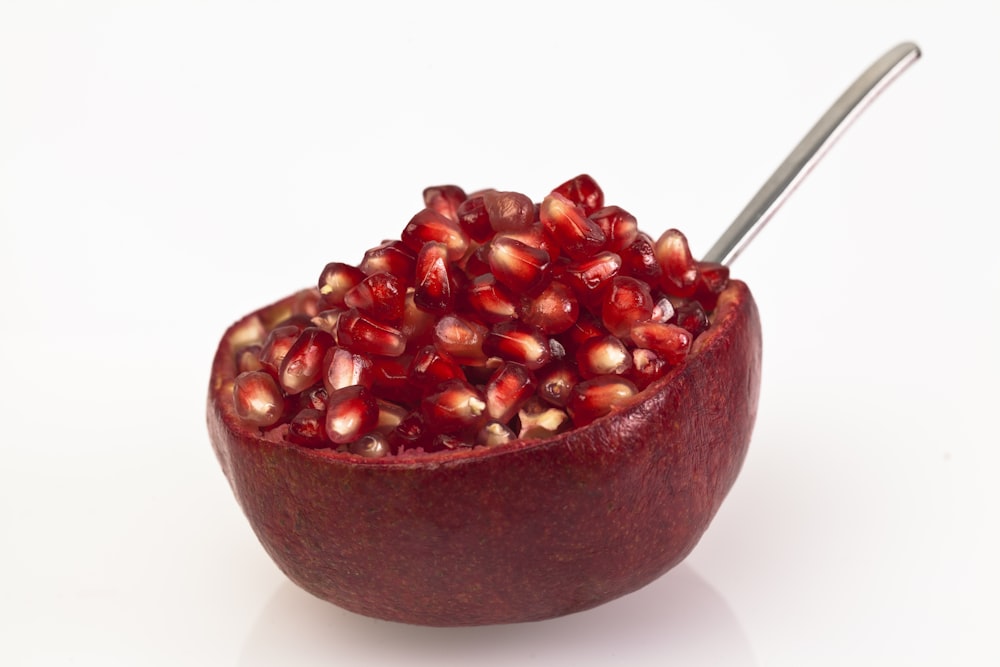 a bowl of pomegranates with a spoon in it