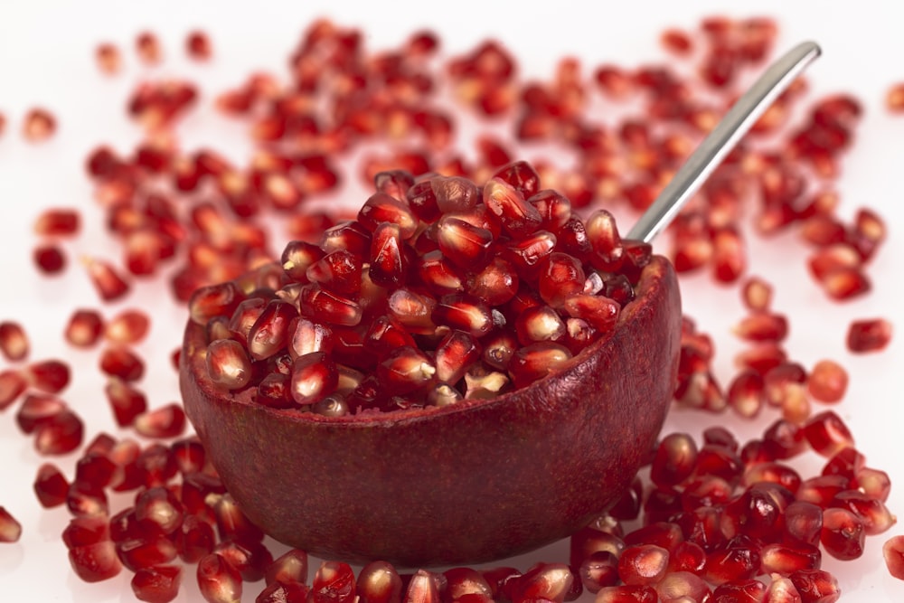a bowl filled with pomegranate on top of a white table