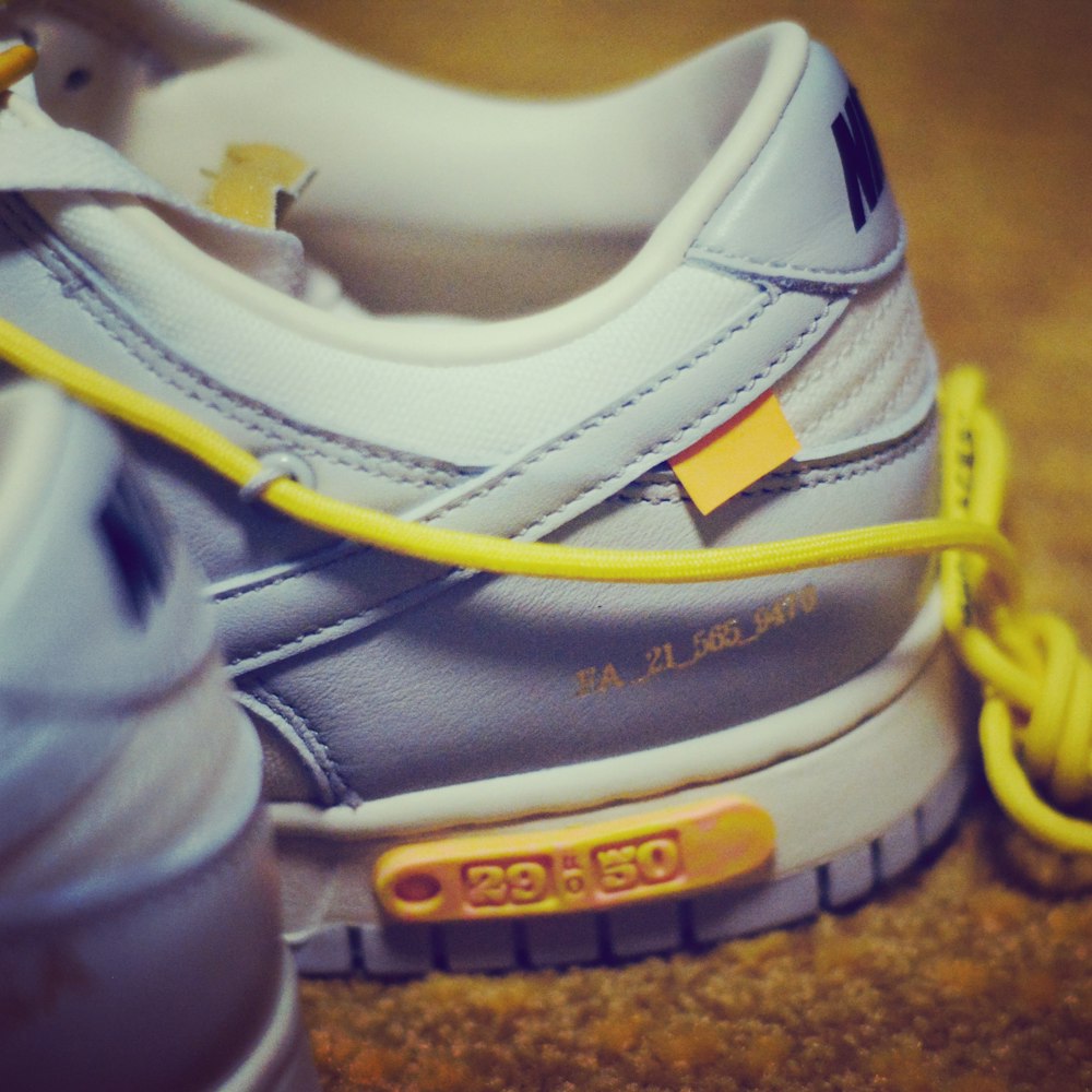 a pair of sneakers with a yellow shoelace