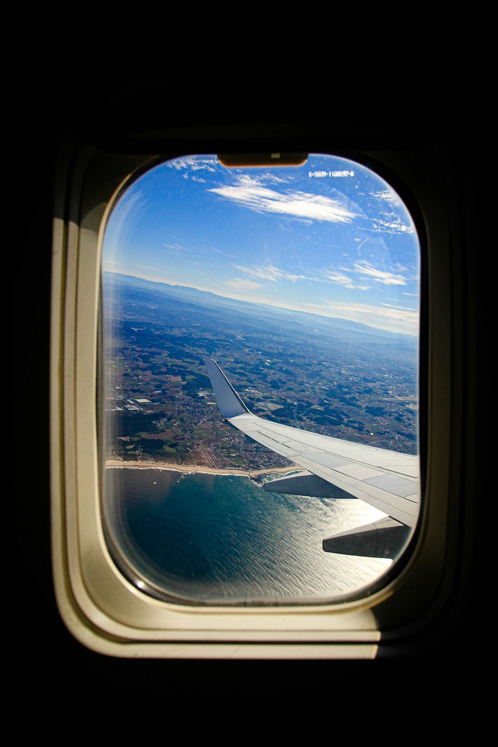 an airplane window with a view of a body of water