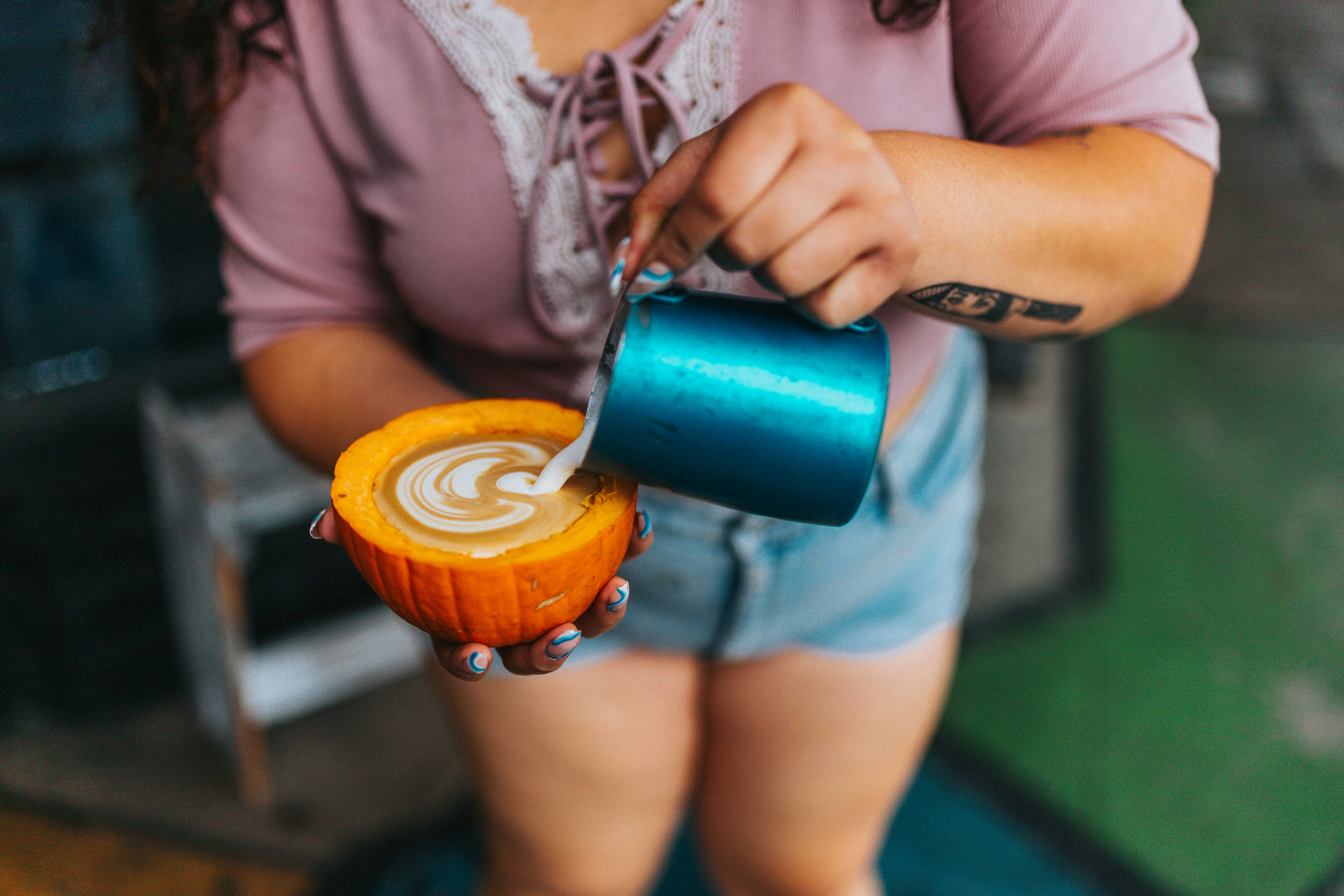 Woman pouring latte art into an orange cup
