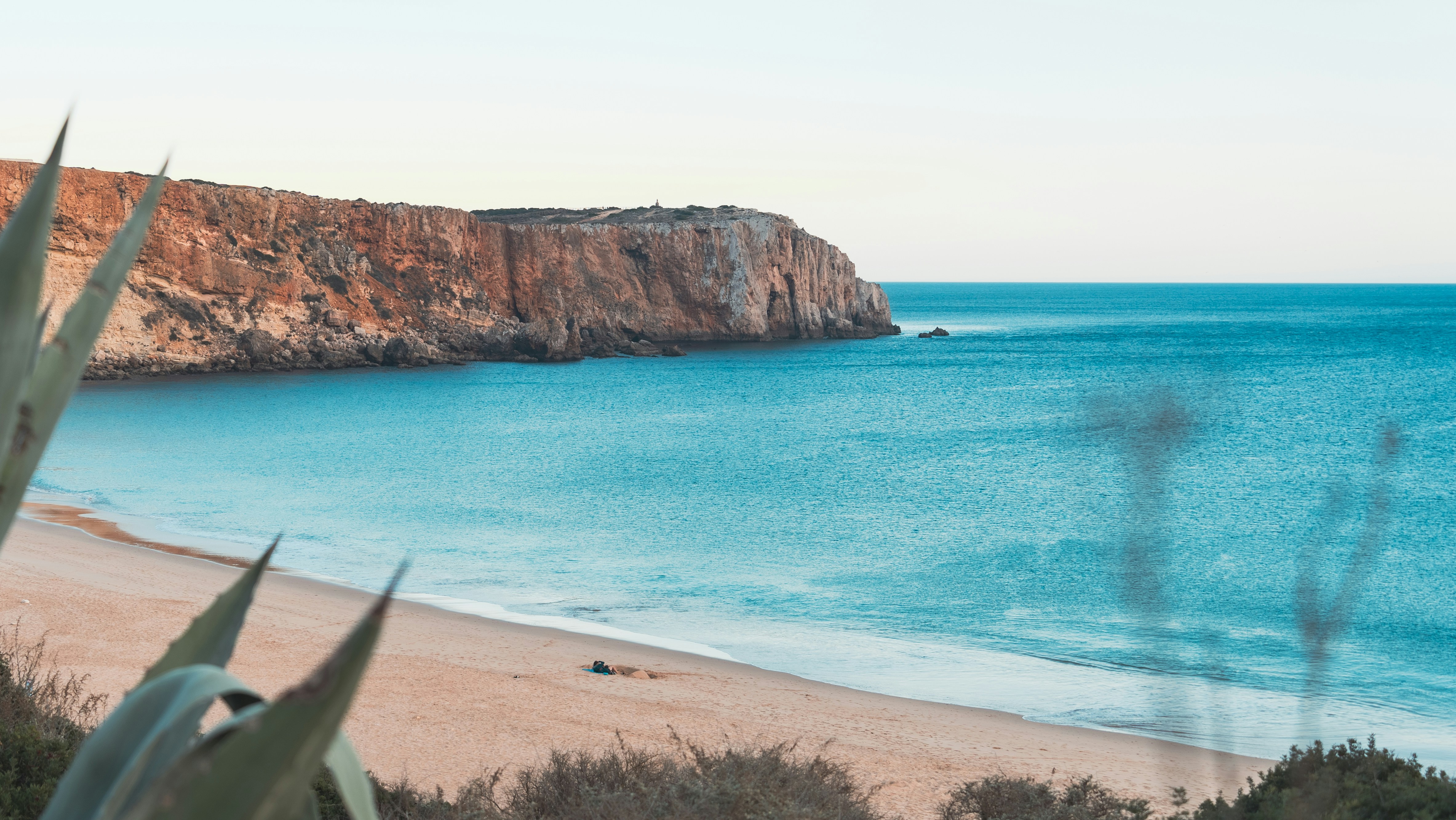a view of a beach with a cliff in the background