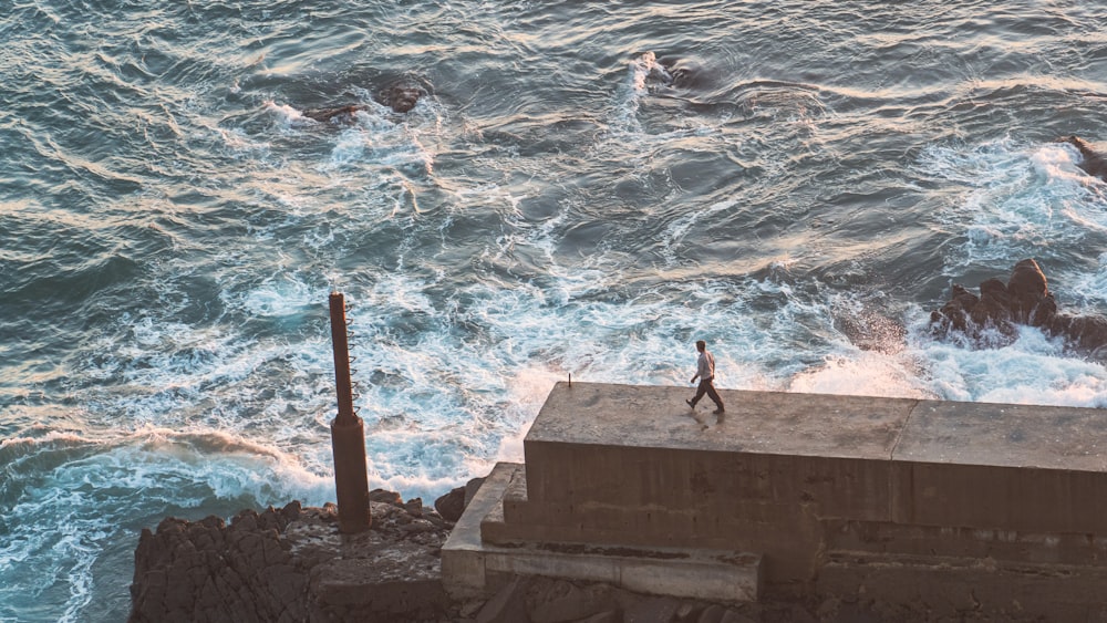 a person walking along the edge of a cliff near the ocean