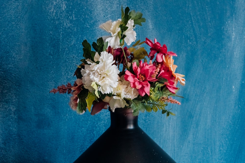 a black vase with a bunch of flowers in it