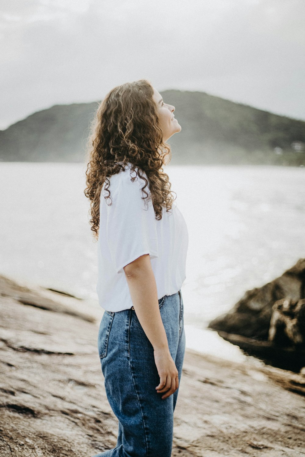 a woman standing on top of a beach next to the ocean