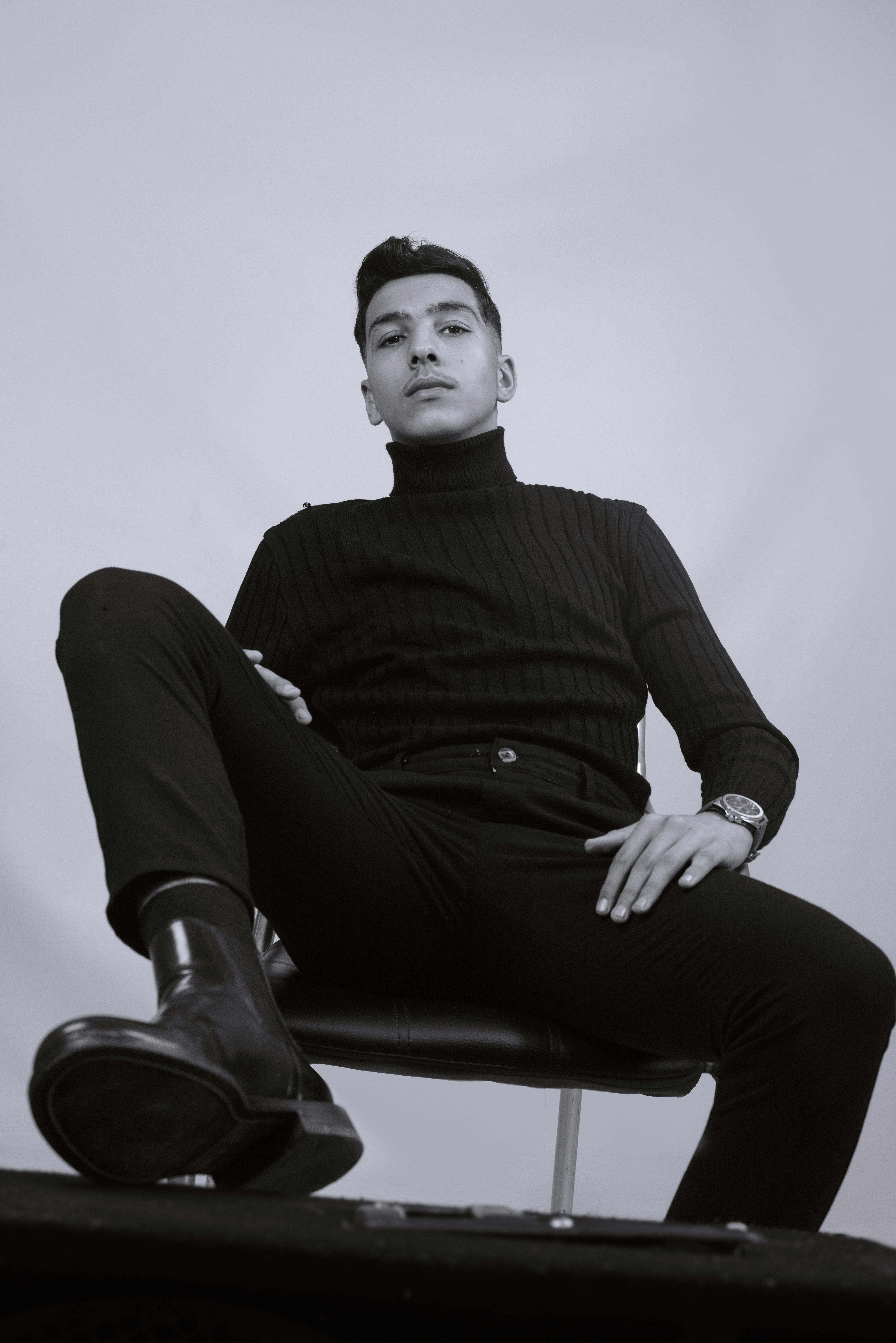 Un homme assis sur une chaise, les jambes croisées photo Photo Gris