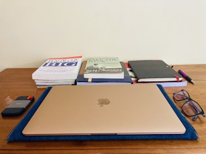 Stacks of multidisciplinary journals neatly arranged on a wooden desk with a laptop.