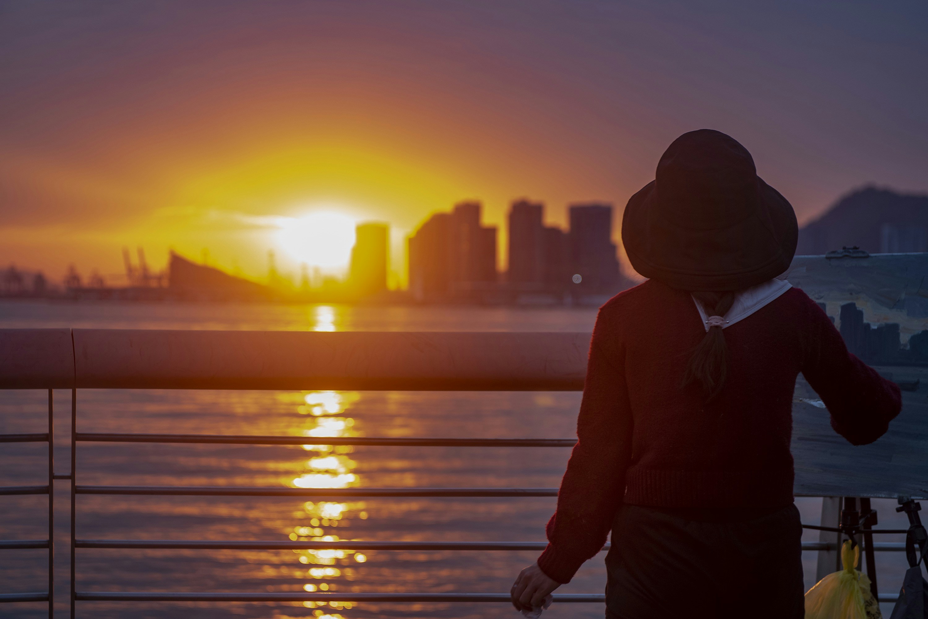 a person standing on a boat watching the sun set