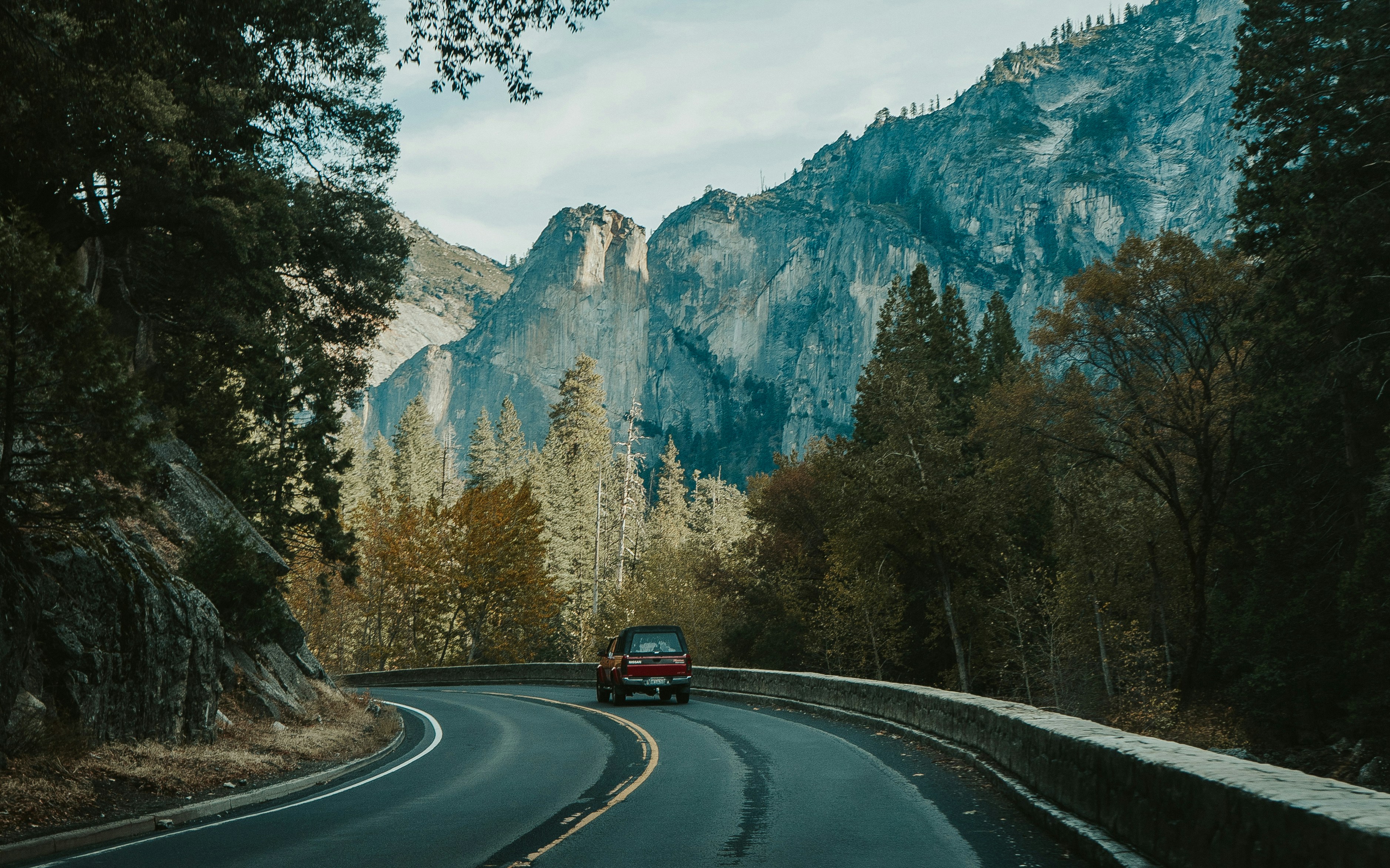 a car driving down a road in front of a mountain