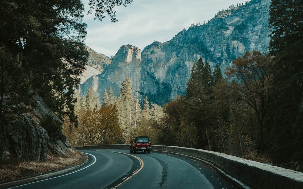 a car driving down a road in front of a mountain