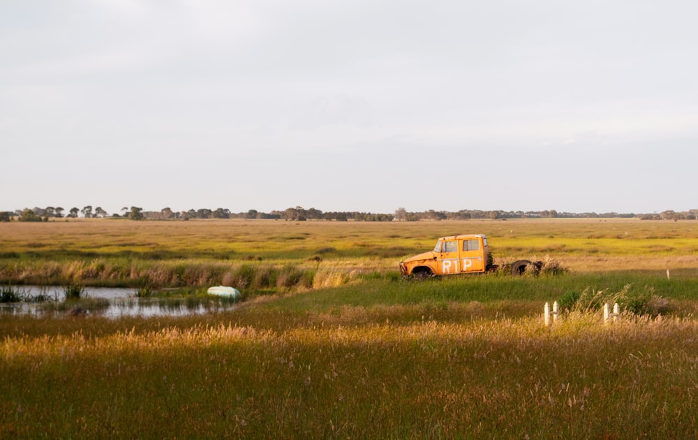 a truck parked in a field next to a body of water