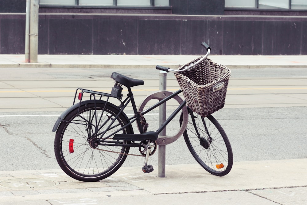 a bicycle parked next to a pole with a basket