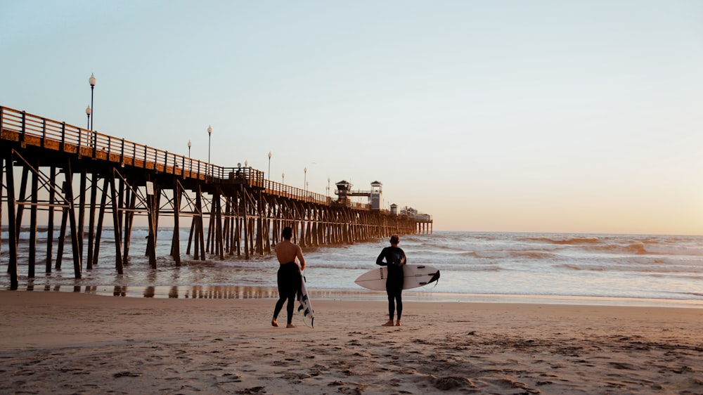 a couple of people standing on top of a sandy beach