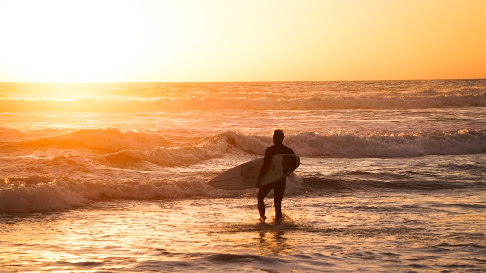 a man holding a surfboard while standing in the ocean