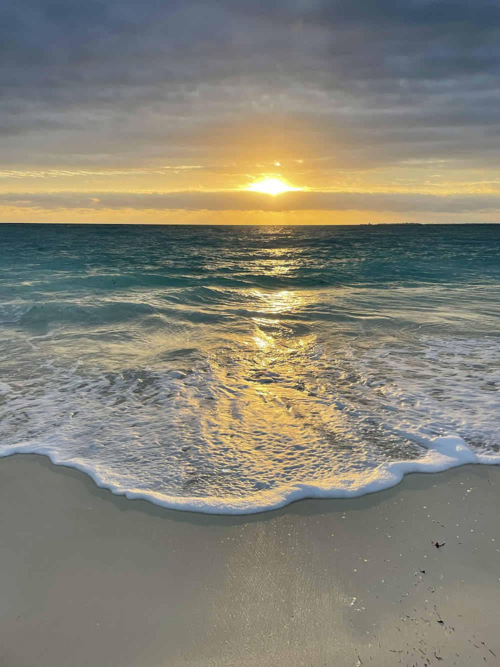 the sun is setting over the ocean on the beach