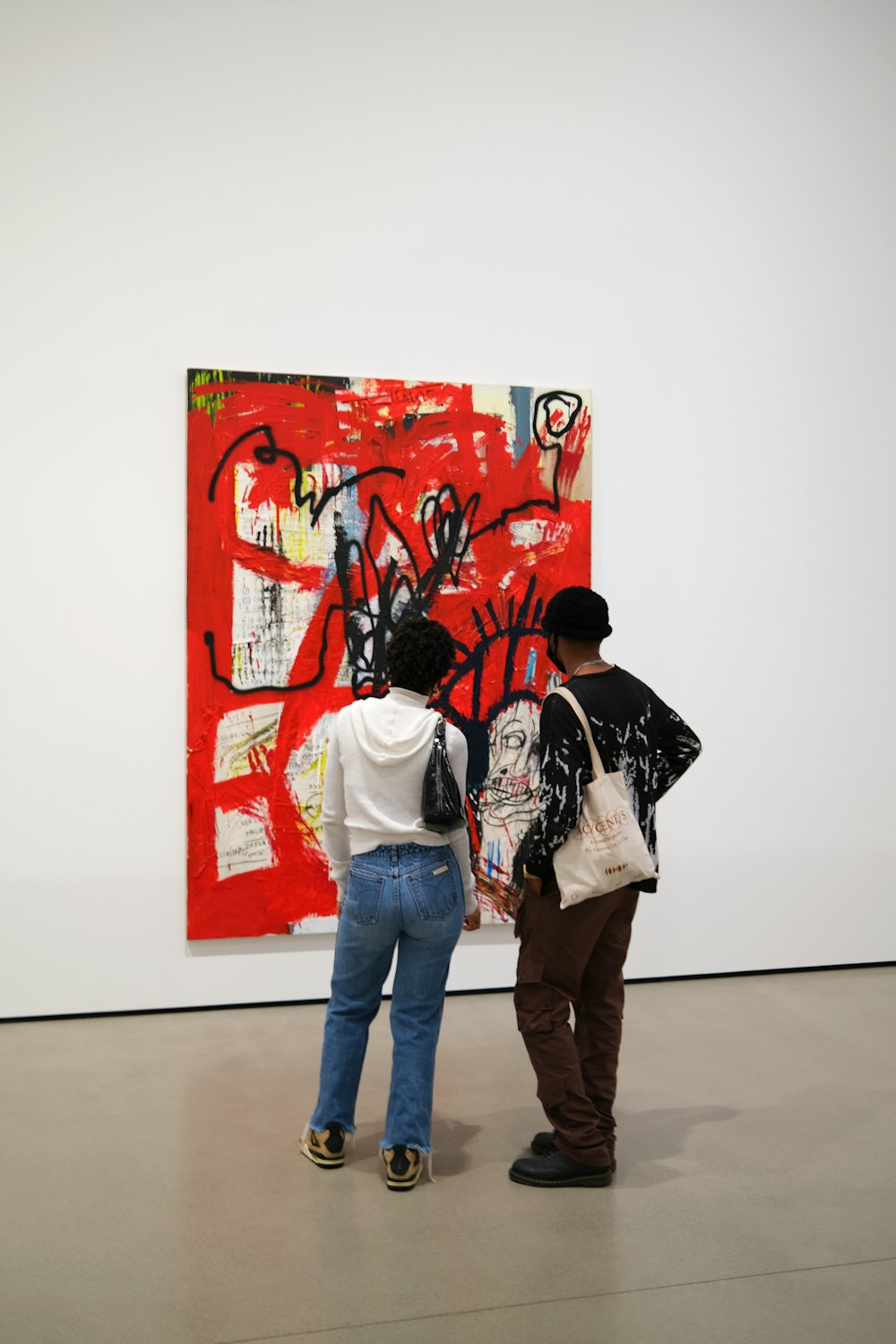 two people standing in front of a painting