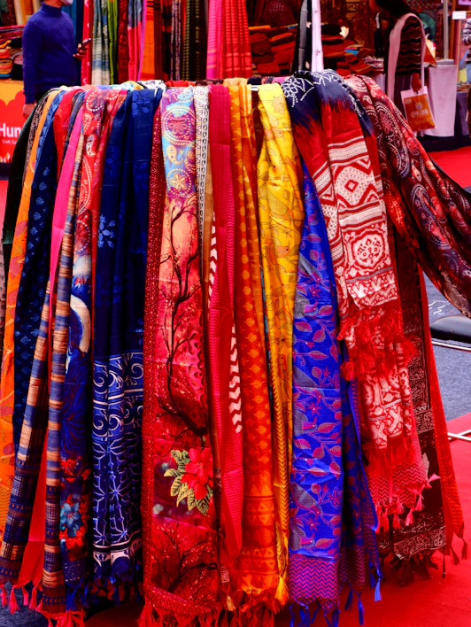 A vibrant display of colorful scarves and hats hanging on rustic wooden racks.