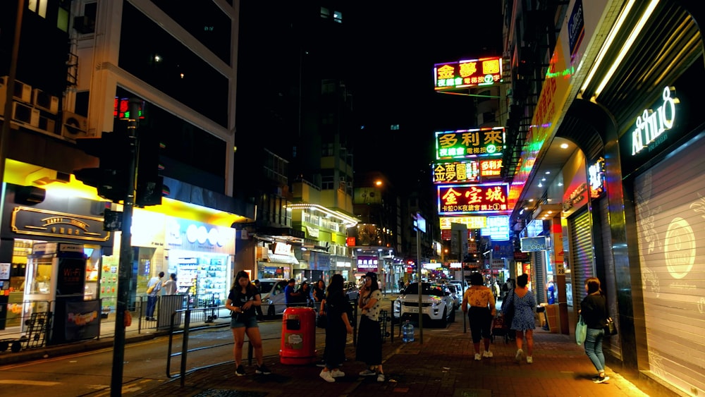 a group of people walking down a street at night