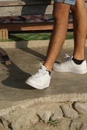 Denim shorts laid out on a concrete surface with sunlight casting shadows.