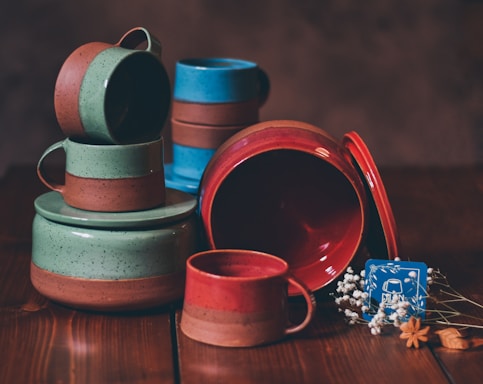 a stack of ceramic dishes and cups on a wooden table
