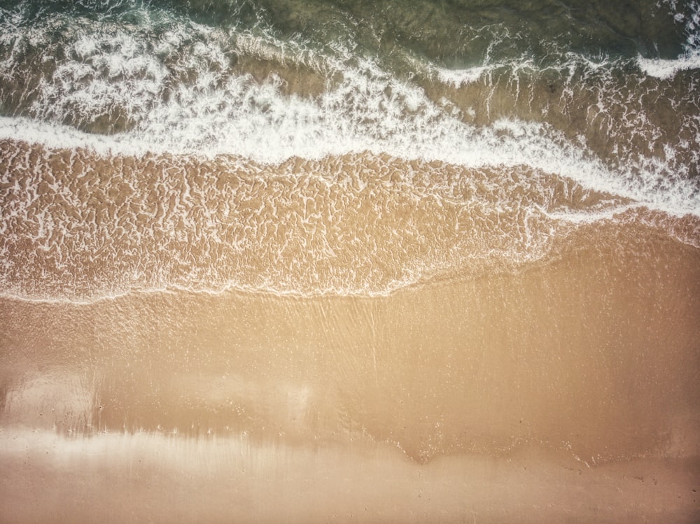 uma vista aérea de uma praia com ondas entrando