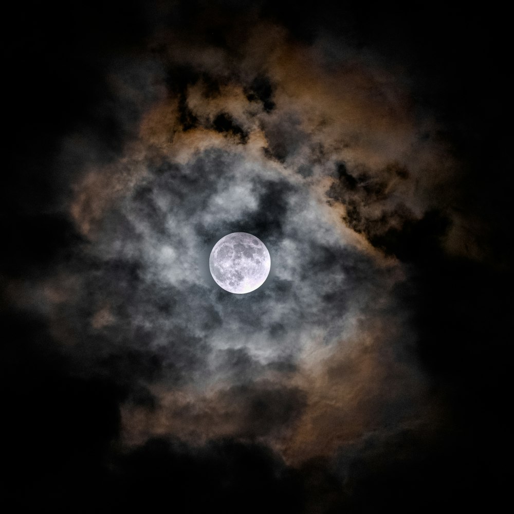 a full moon is seen through the clouds