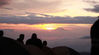Sunset view from a mountain peak with club members silhouetted against the sky.