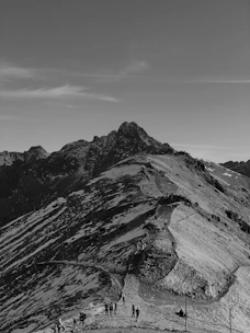 A seasoned guide leading a group through a rocky mountain path under clear skies.