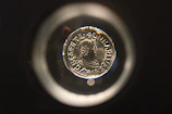 Close-up of an expert examining an ancient coin under a magnifying glass.