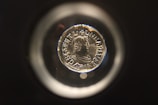 A collector examining a coin through a magnifying glass.