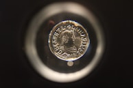 A collector examining an old coin under a magnifying glass.
