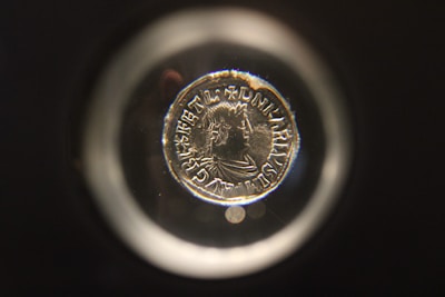 A collector carefully examining an ancient coin under a magnifying glass.