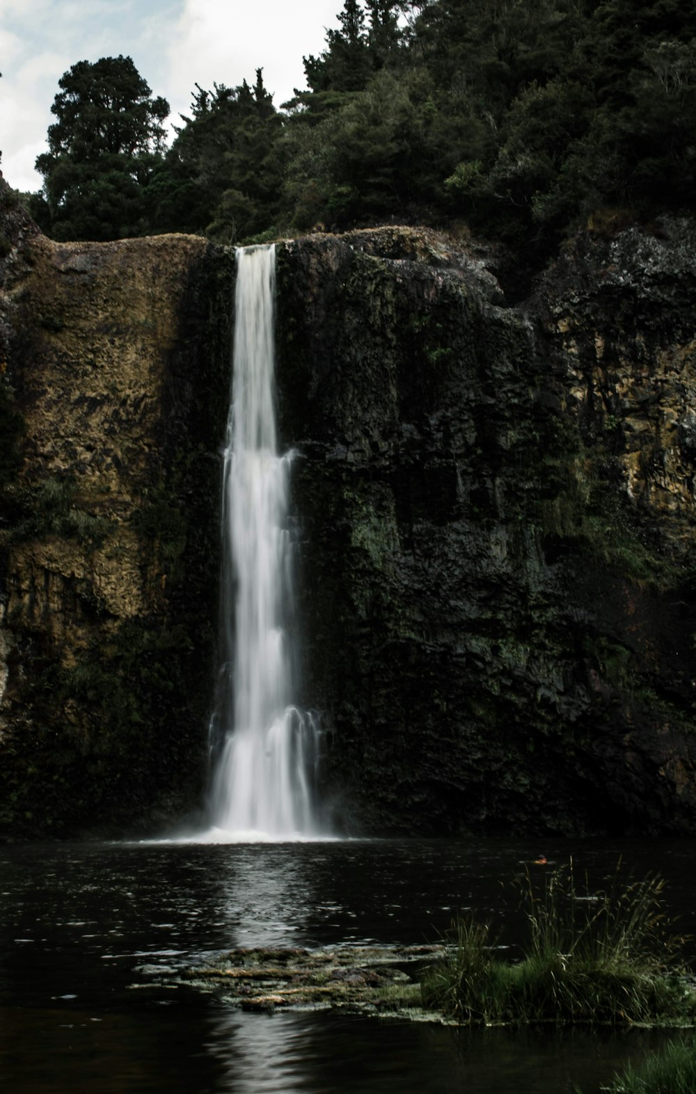 a large waterfall with a man standing in front of it