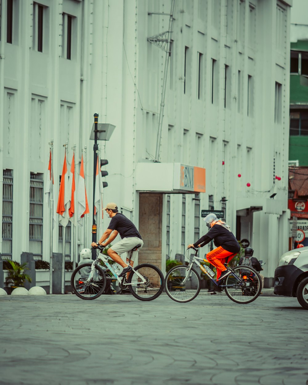 a couple of men riding bikes down a street