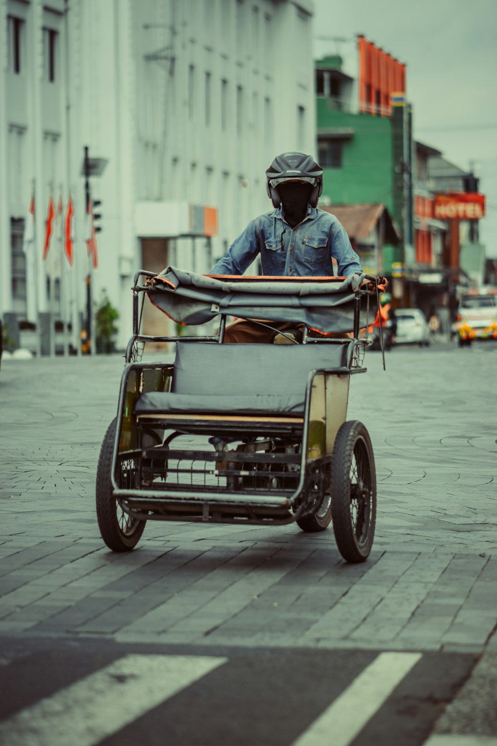 a man riding a cart down a city street