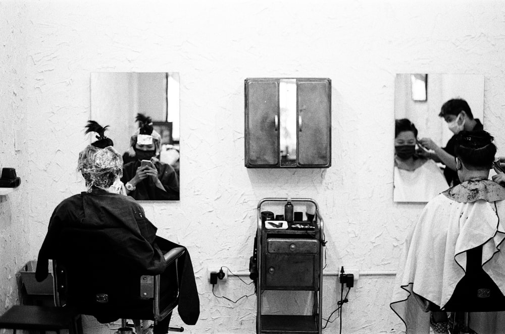 a black and white photo of a woman getting her hair cut