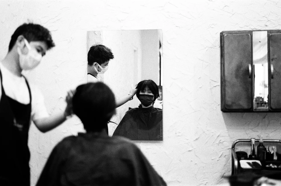 Two hairdressers work together in a clean, professional salon with a mirrored wall behind them