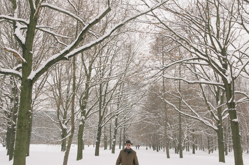a man walking through a snow covered park