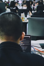 An office scene showing employees engaging with AI-powered chatbots on multiple devices.