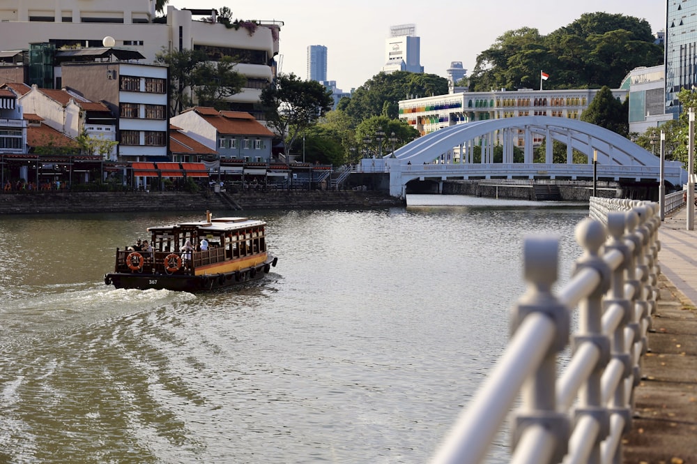 a boat traveling down a river next to a bridge