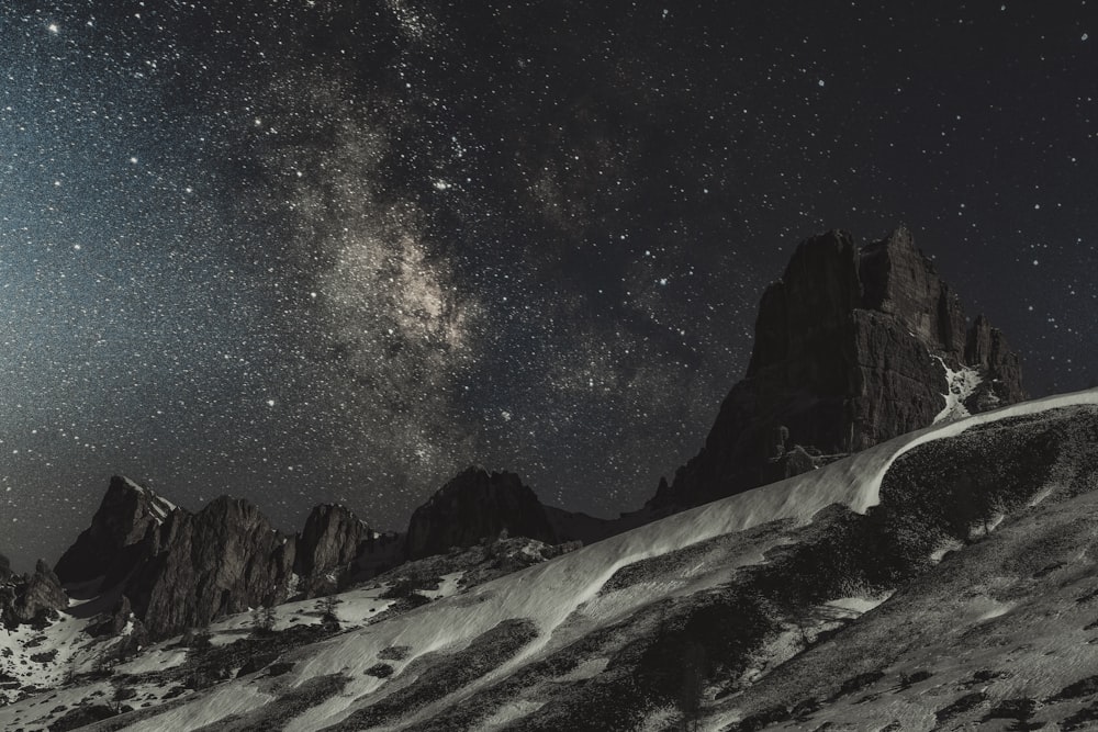 the night sky with stars above a mountain range