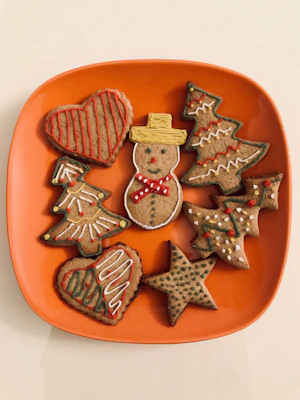 Colorful assortment of decorated sugar cookies shaped like stars and hearts on a festive plate.